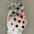 Clear phone case with black polka dots held by a hand against a neutral background