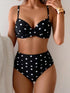 Black polka dot bikini set worn by a person against a neutral background