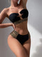 Black bikini with gold embellishments on a neutral background