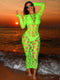 Woman in a neon green dress with cut-out patterns standing on a beach at sunset.