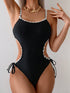 Black swimsuit with white lace details on a neutral background
