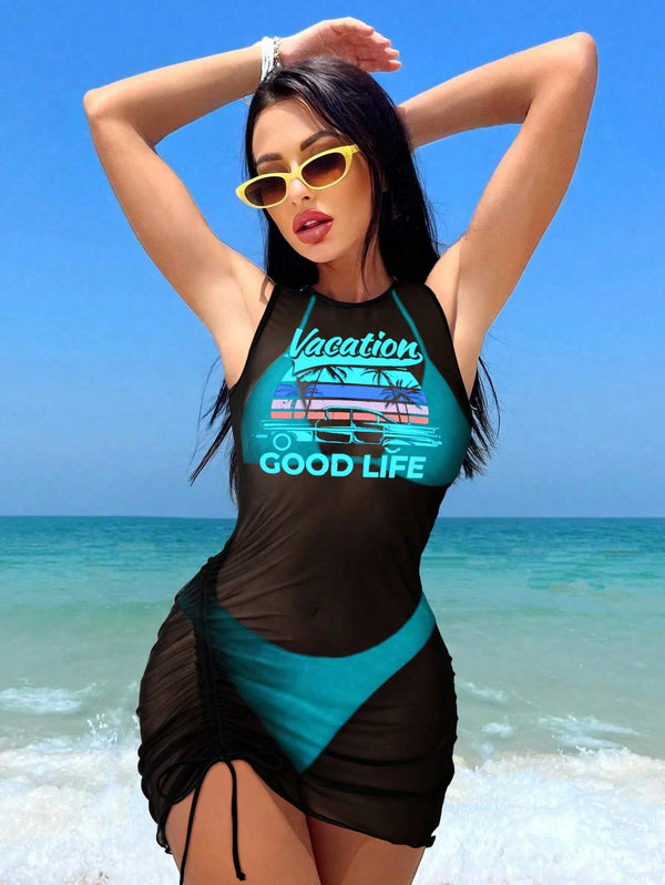 Woman in a black and teal swimsuit with 'Good Life' text on a beach