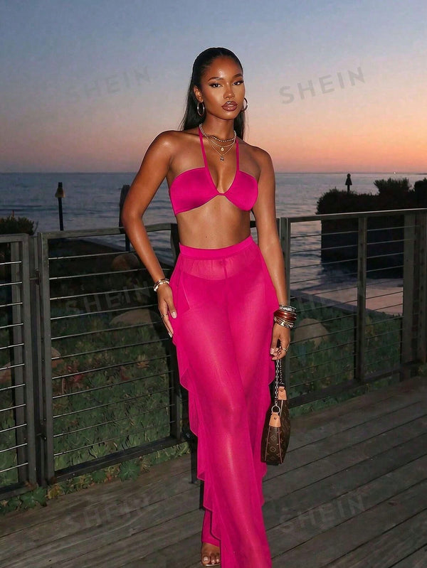Woman in a bright pink outfit standing on a wooden deck with ocean view