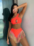Woman wearing a bright orange bikini with colorful fringe details, standing by a window.