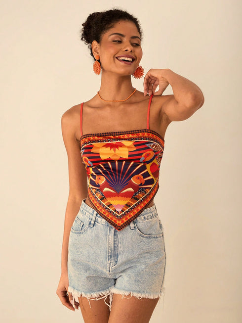 Woman wearing a colorful patterned top and denim shorts on a beige background