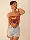 Woman wearing a colorful patterned top and denim shorts on a beige background