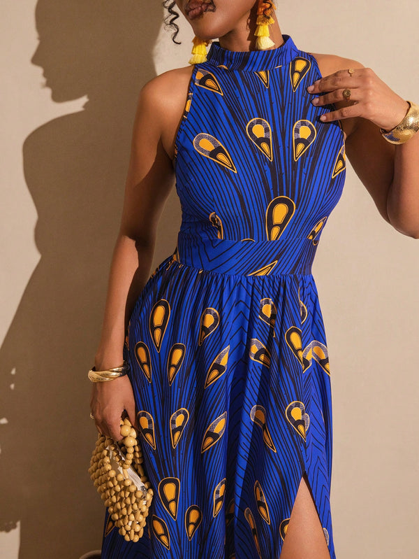 A woman wearing a sleeveless high-neck blue dress with a yellow and black peacock feather pattern, holding a beaded clutch against a beige wall.