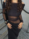 Person wearing a black off-shoulder dress with sheer panels on a concrete surface.