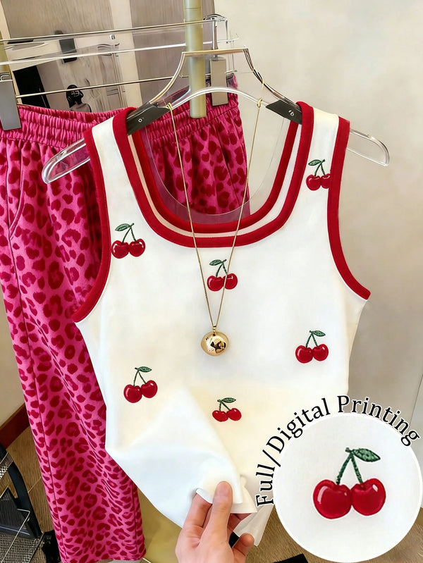 White tank top with red cherry design and pink leopard print pants on a hanger.