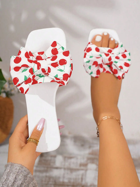 White sandals with red cherry pattern worn by a person on a blurred background