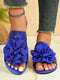 Blue sandals with large floral decorations on a neutral background