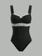 A black one-piece bodysuit with white lace trim across the bust and waist, featuring thin shoulder straps and a small white bow at the center neckline, shown against a solid gray background.