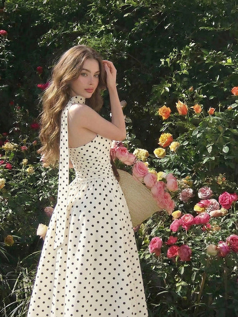 Woman in a polka dot dress standing among flowers