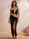 Woman wearing a black and gold one-shoulder dress with a high slit, standing against a textured white wall.