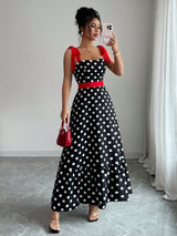 Woman taking a mirror selfie wearing a black polka dot dress with red accents.