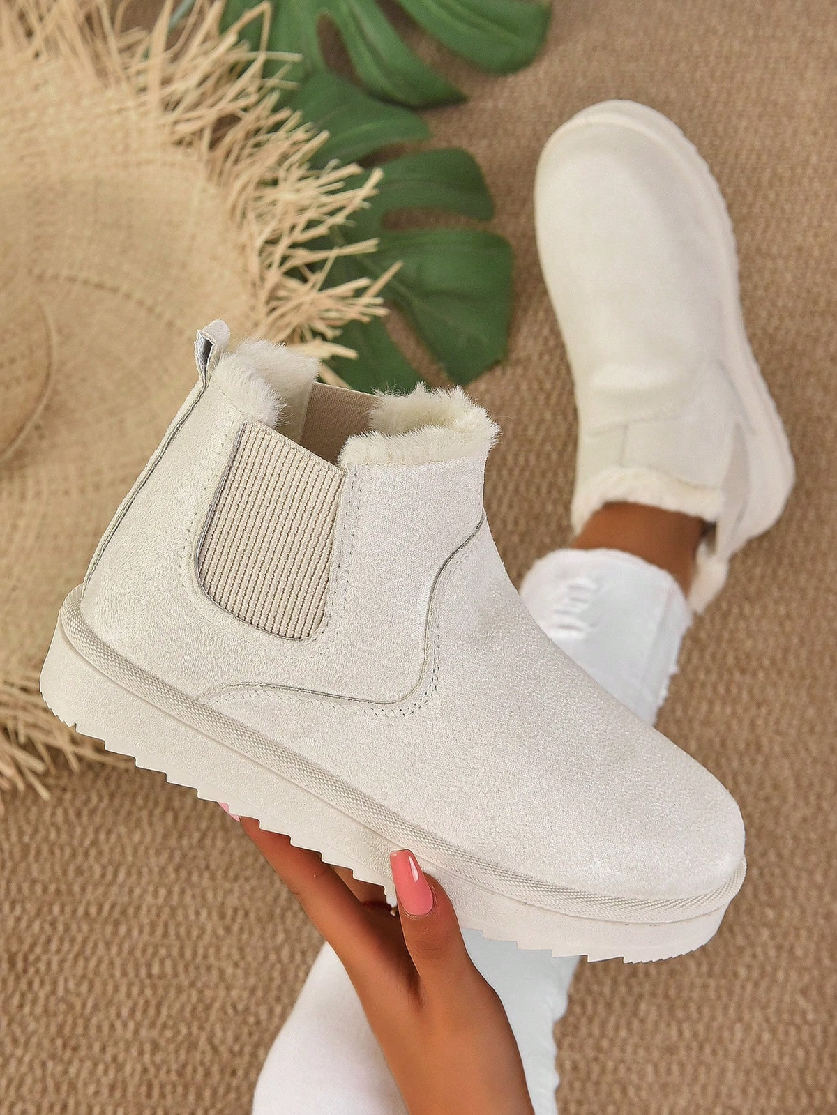 White ankle boots being worn on a textured surface with plants in the background