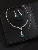 Silver-tone jewelry set featuring a necklace and matching drop earrings with emerald green teardrop stones and clear rhinestone accents, displayed on a black presentation box.
