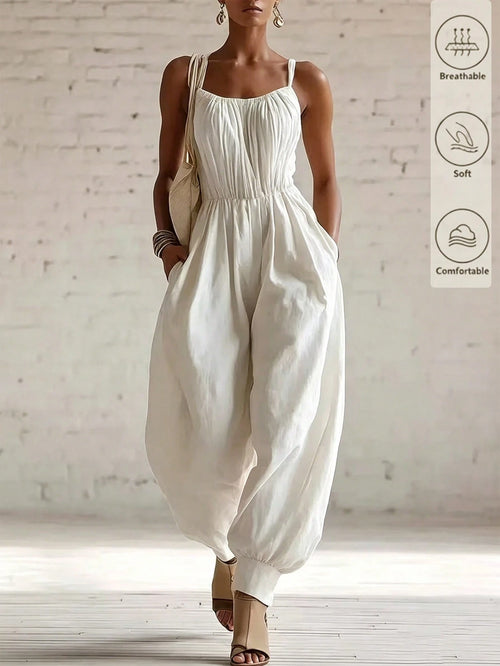 A woman models a cream-colored sleeveless jumpsuit with a gathered bodice and voluminous balloon hems, set against a white brick wall background. A vertical graphic on the right lists product features: breathable, soft, and comfortable.