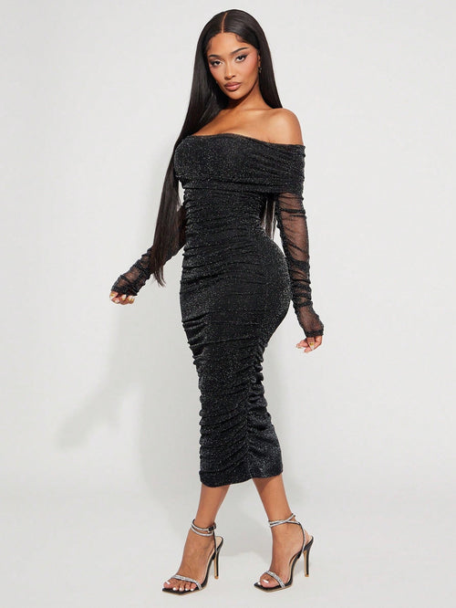 Woman wearing a black off-shoulder dress with sheer sleeves on a white background