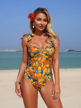 Woman in a colorful swimsuit on a beach with clear blue water and sky.