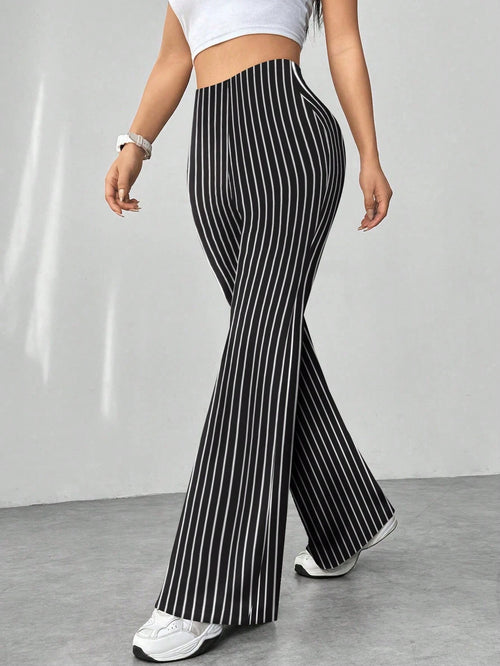 Person wearing black and white striped pants on a plain background