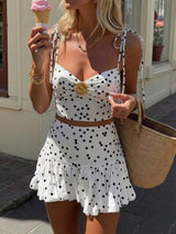 Woman in a polka dot dress holding an ice cream cone outdoors.